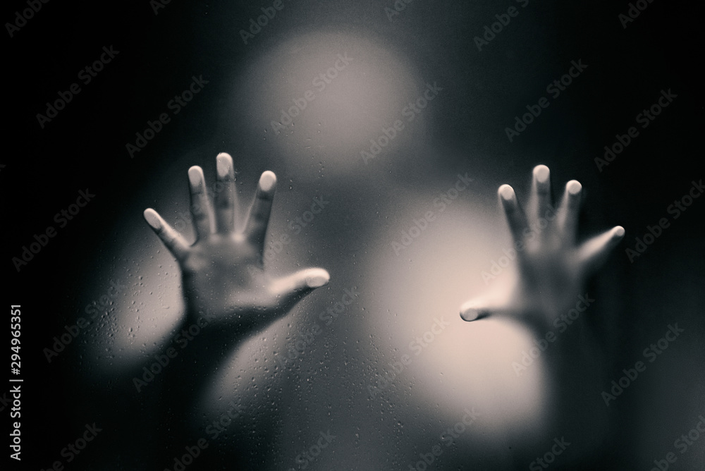 Black color version of Creepy man looking behind the frosted glass and holding it with two hands.
