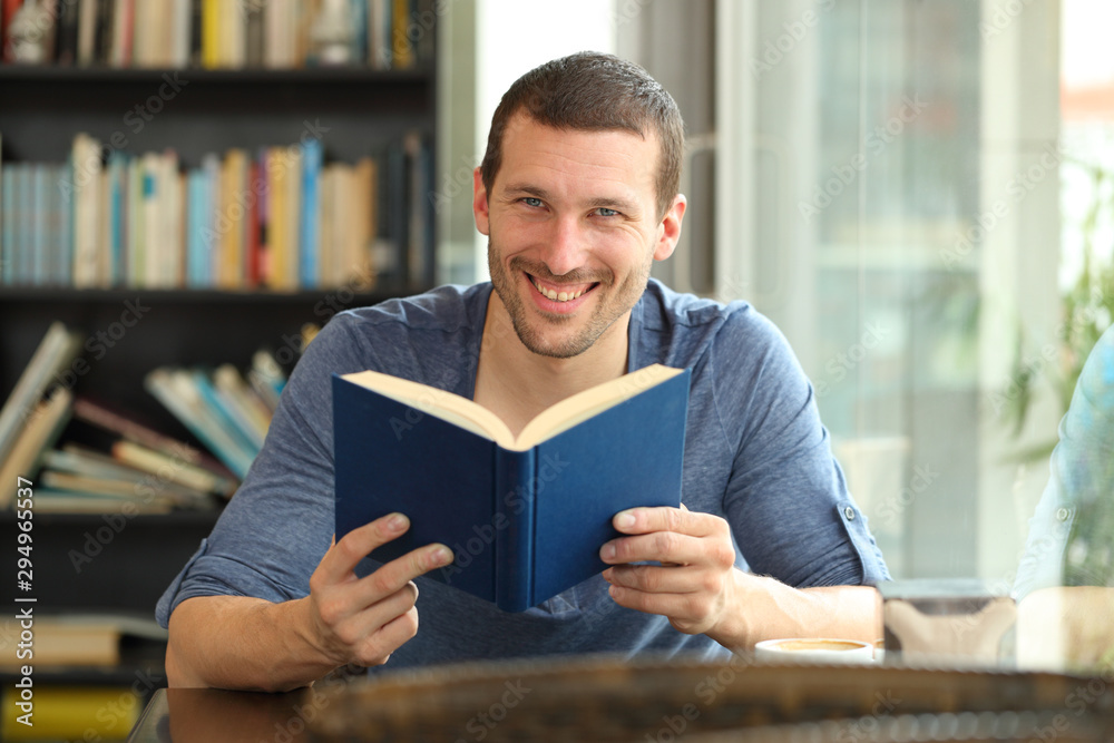 Happy man holding a paper book posing looking at camera Happy man holding a paper book posing looking at camera