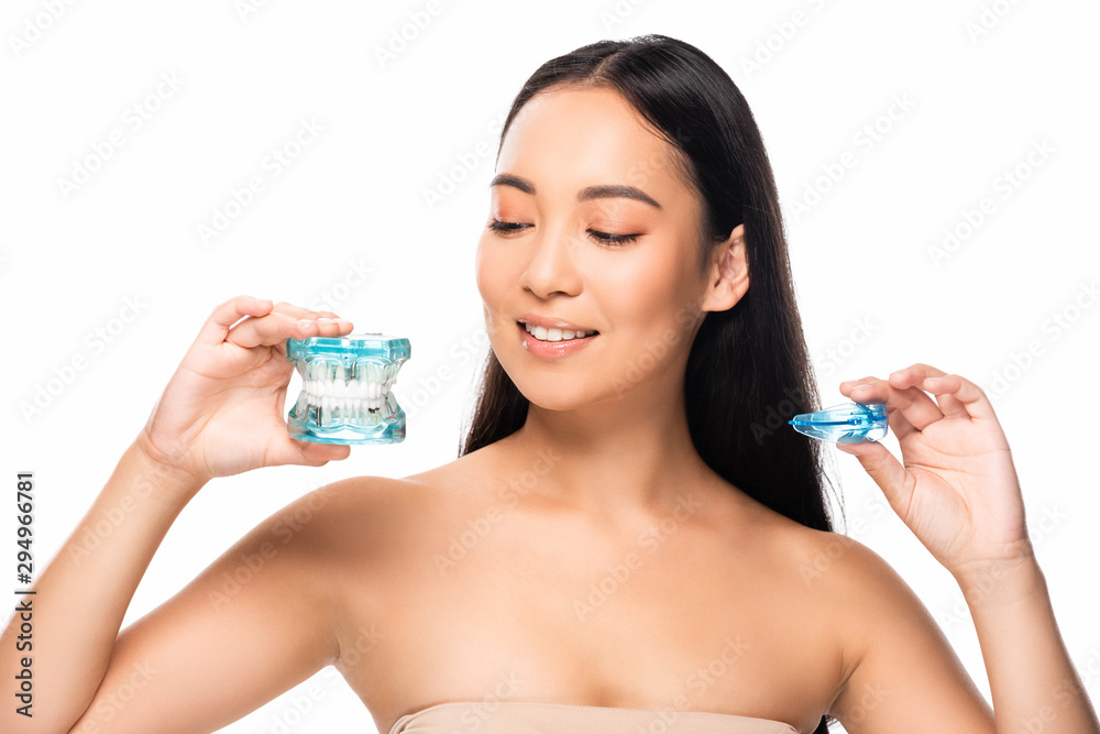 smiling asian woman holding jaw model and mouth guard isolated on white smiling asian woman holding jaw model and mouth guard isolated on white
