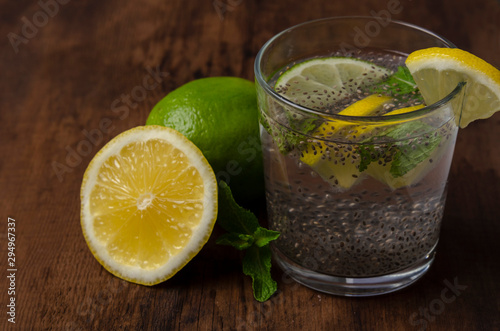 Chia seeds drink with water in glass with lime lemon mint wooden background © Anton