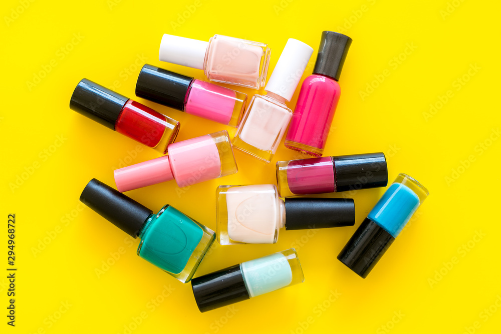 Choose nail polish. Polish bottels on yellow background top view copy space