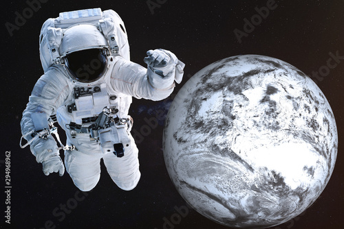 Fototapeta Naklejka Na Ścianę i Meble -  Giant Astronaut near the Dead frozen Earth planet of Solar system. Science fiction. Elements of the image are furnished by NASA
