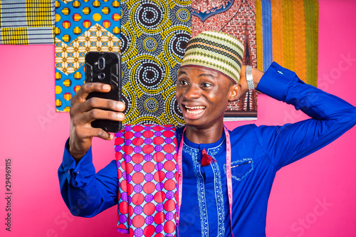 a youn nigerian tailor feels very surprise with what he saw on his phone. photo
