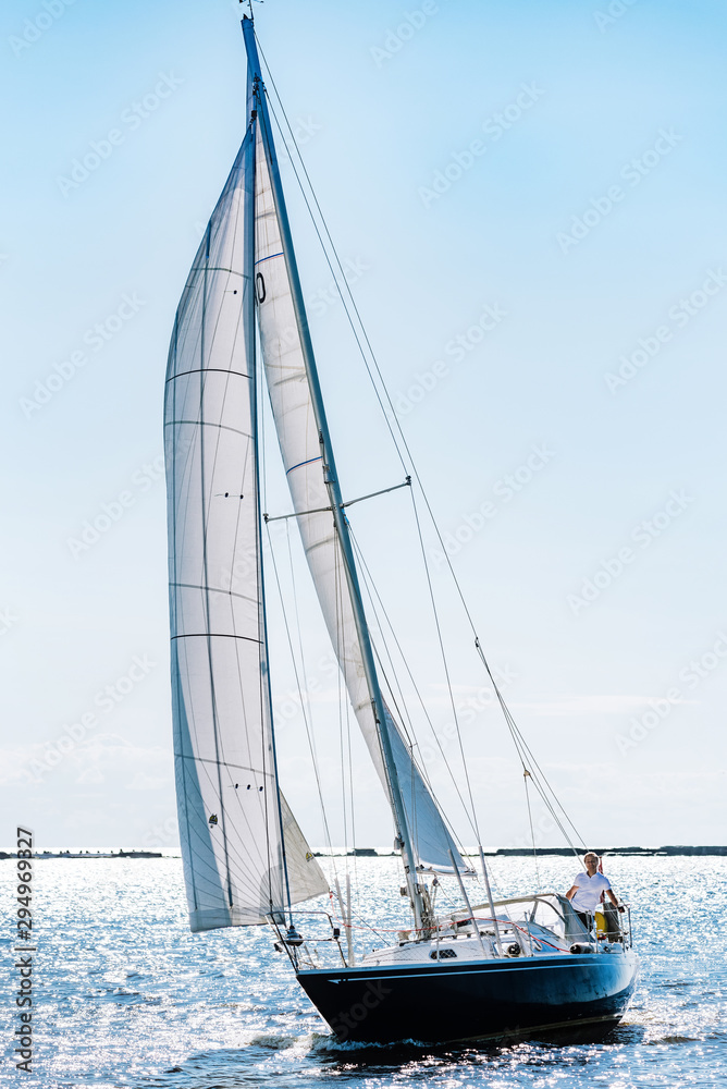 Fototapeta premium Aerial photography of yacht with white sails in dark blue open space. The good wind fills sails on a sunny summer day.