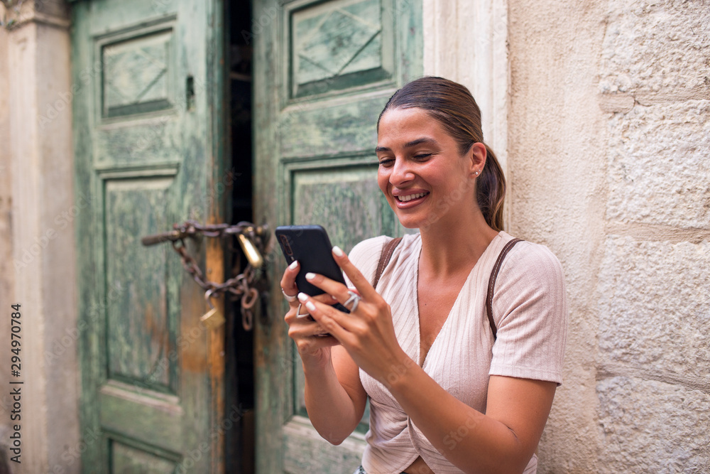 Happy young female tourist using mobile phone in town Happy young female tourist using mobile phone in town