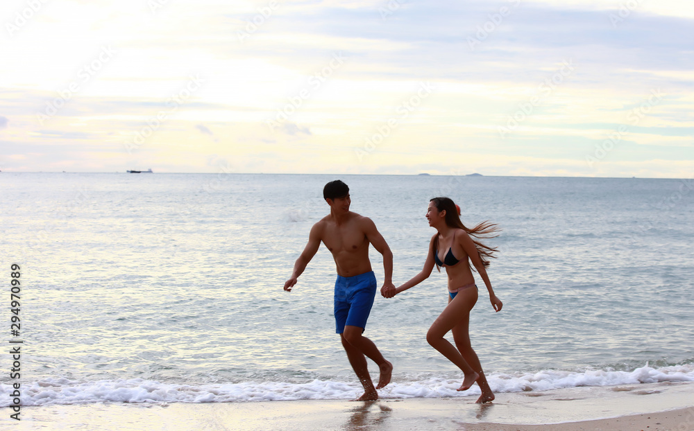 A couple play running on beach, happy couple running on the beach