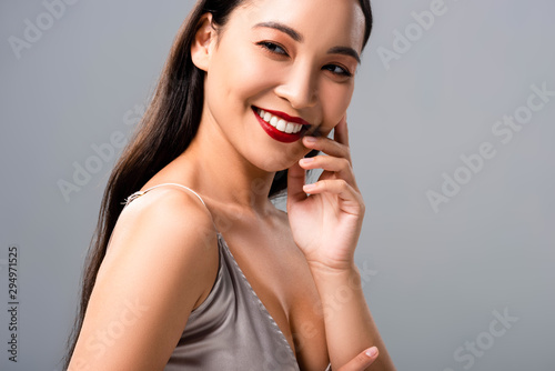 happy asian woman in satin dress with red lips isolated on grey