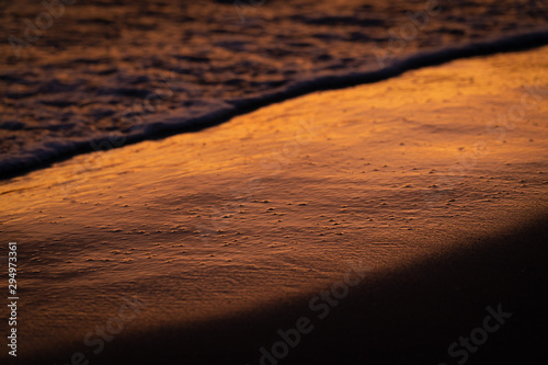 Orange sunset landscape with sea and beach sand. Sun reflection in foamy sea. Cinematographic image. Romantic evening seascape with sunset. Exotic nature landscape