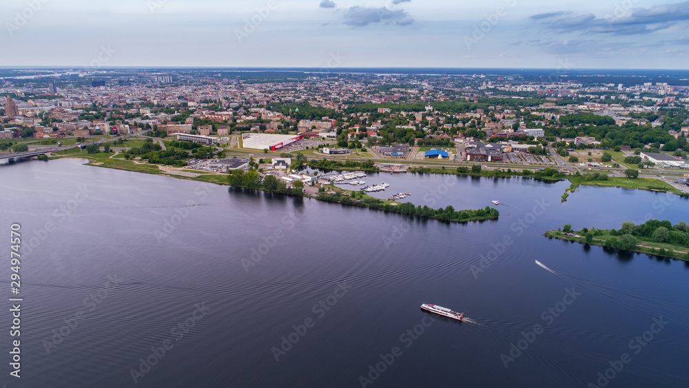 Fototapeta premium Tourist ship travels down the river Daugava in Riga, Latvia. Captured from above with a drone.
