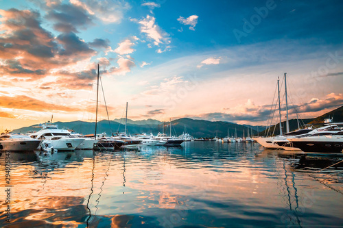 Luxury yachts and motor boats docked in marina Porto Montenegro in Mediterranean sea at sunset.