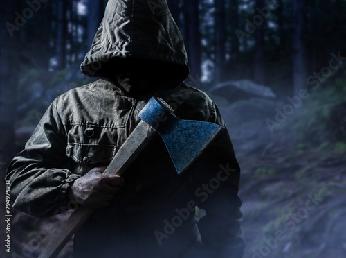 Scary killer with an axe in woods. photo