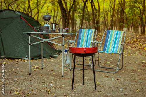 Camping tent with desk and chairs in forest, сamping cookware set outdoors