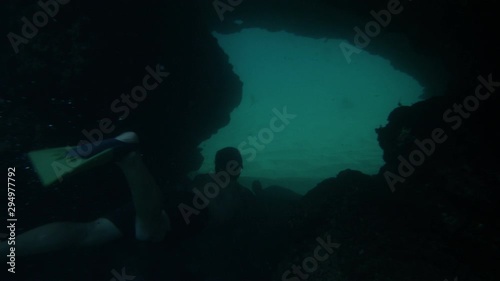 Wallpaper Mural A medium shot of a man wearing a set of foot flippers swimming and passing through a dimly lit underwater cave. Torontodigital.ca
