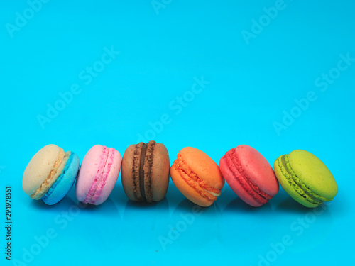Colorful french macarons (macaroons) cake, delicious sweet dessert on blue background with copyspace, food background concept.