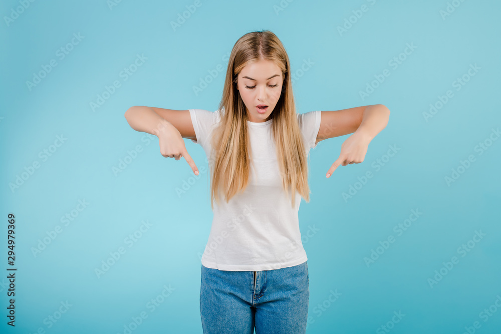 cheerful blonde woman pointing fingers down isolated over blue