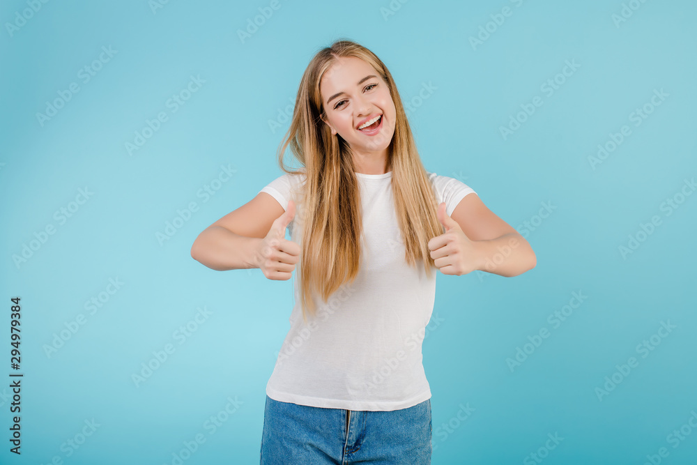 Fototapeta premium happy smiling blonde woman with thumbs up isolated over blue
