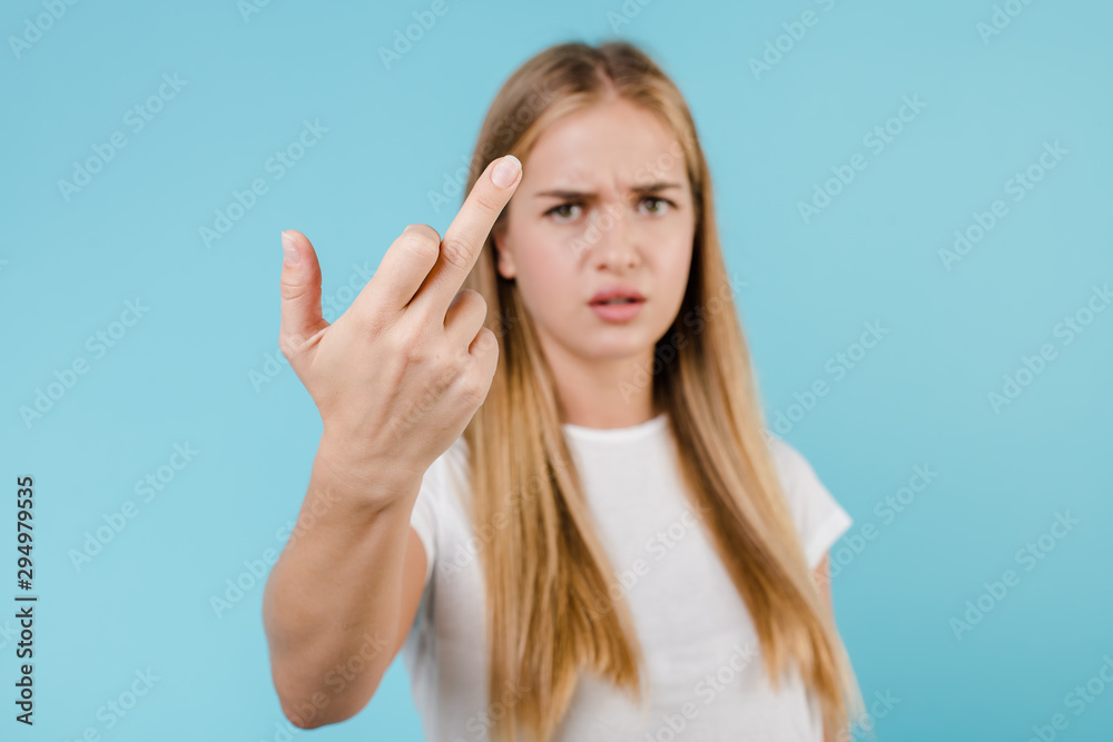 angry young woman showing middle finger isolated over blue