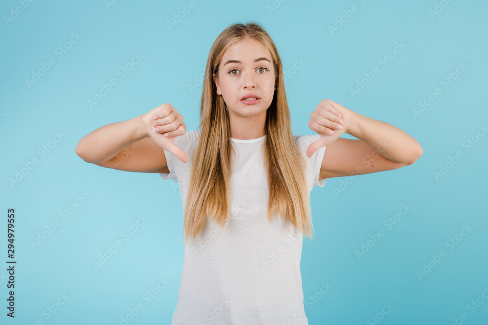 unhappy young blonde woman showing thumbs down isolated over blue unhappy young blonde woman showing thumbs down isolated over blue