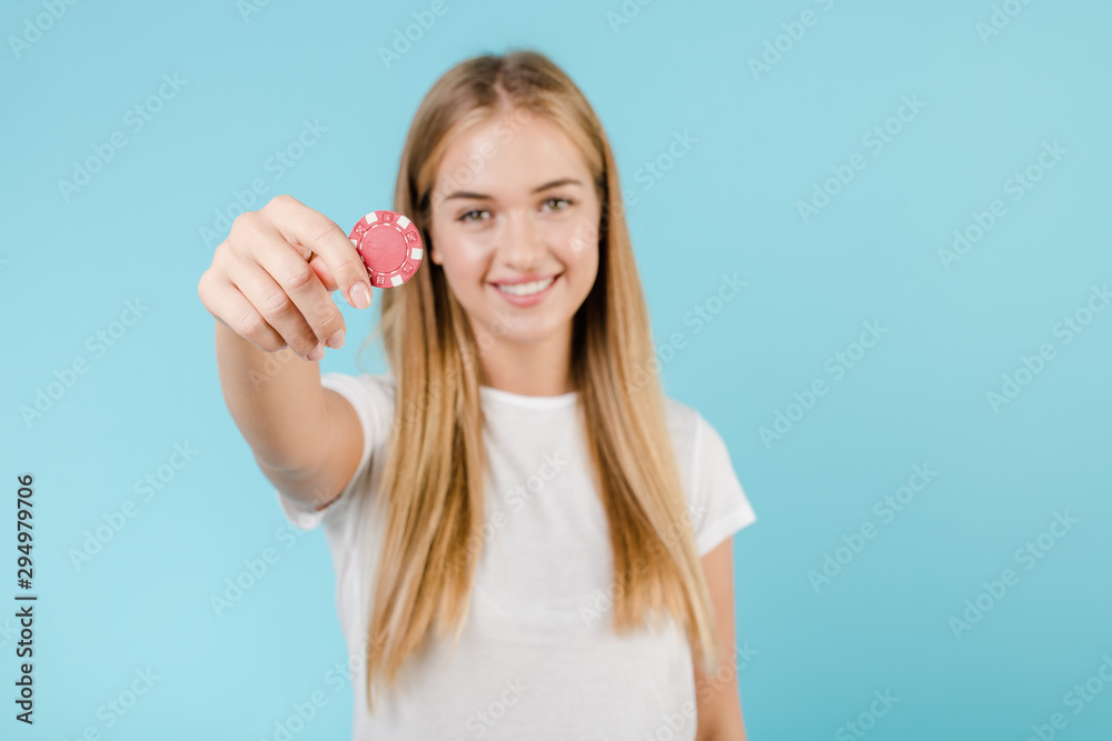beautiful smiling blonde woman with poker chip from online casino isolated over blue beautiful smiling blonde woman with poker chip from online casino isolated over blue