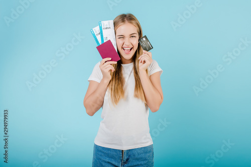smiling happy woman has plane tickets and passport with credit card isolated over blue