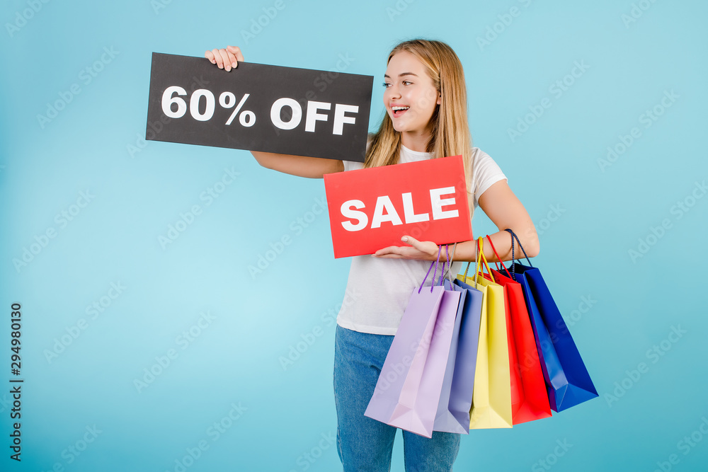 smiling girl with 60% sale sign and colorful shopping bags isolated over blue smiling girl with 60% sale sign and colorful shopping bags isolated over blue