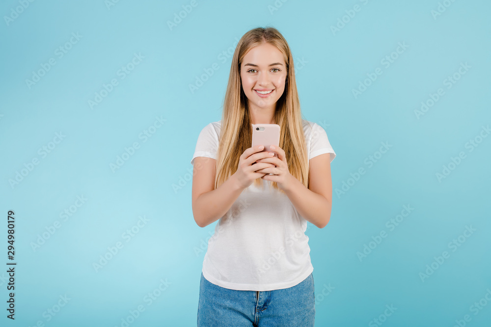 smiling young blonde woman looking at the phone isolated over blue smiling young blonde woman looking at the phone isolated over blue