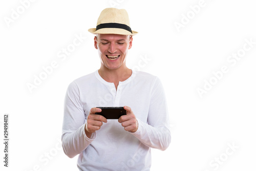 Studio shot of young happy man smiling while using mobile phone