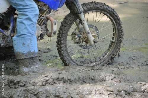 Close up of a dirt bike and rider stuck in a mud puddle.