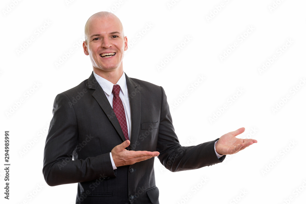 Studio shot of young happy bald businessman smiling while showin Studio shot of young happy bald businessman smiling while showin
