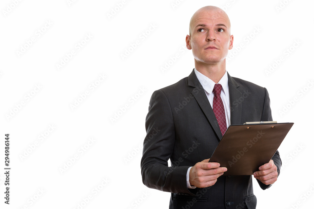 Studio shot of young handsome bald businessman holding clipboard