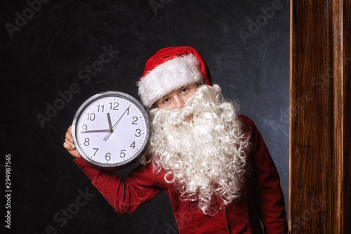Portrait of a boy in a Santa hat with a clock indicating the time