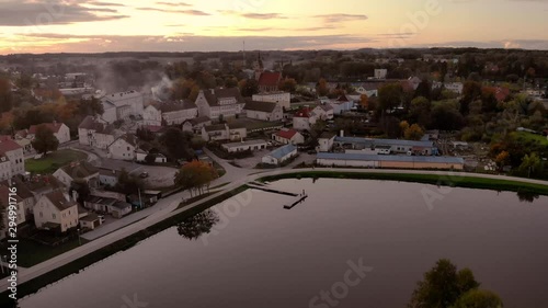 Aerial footage on the pond in the middle of the city, historic town in Poland, recreational path around the lake in the city, ancient buildings of the city, beautiful sunset in Warmia and Mazury photo