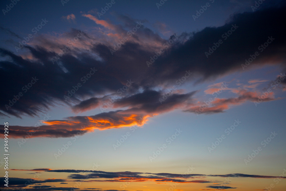 Orange sunrise reflects off bottom of clouds in lightening sky