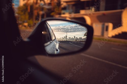The Perth city skyline in the sideview mirror of a car. Beautiful and quiet sunrise over the city with golden light. 