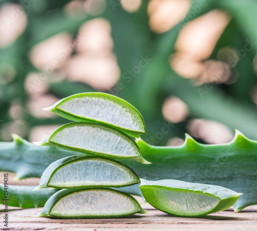 Fresh aloe leaves and aloe gel in the cosmetic jar on wooden table.