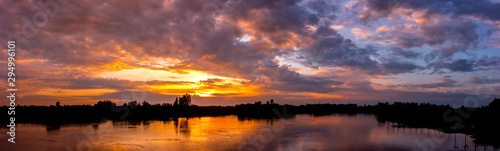 Panorama Reflection of vivid sunset sky reflection in  water.Colorful sunrise with Clouds over Lake at Koh Klang nam , Sisaket province,Thailand,ASIA.