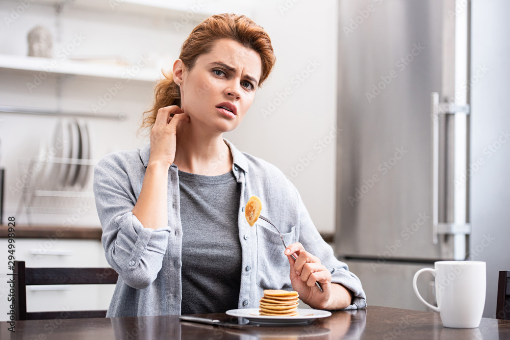 woman looking at camera while touching neck near tasty pancakes woman looking at camera while touching neck near tasty pancakes