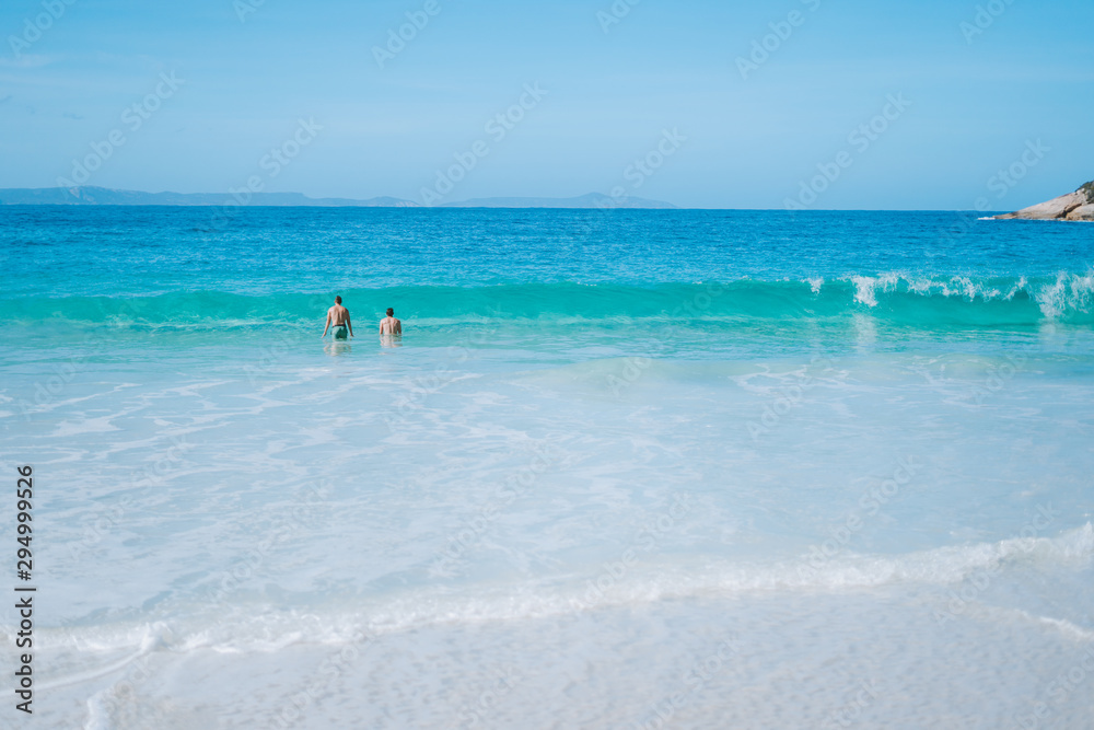 Two boys swimming in the vibrant blue ocean water of Albany, Australia. 