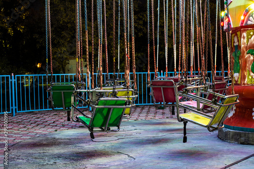 Empty carousel metal seat. Amusement park concept in a city park. photo