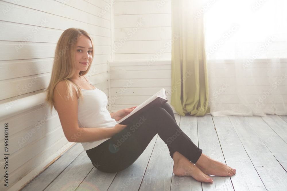 Student and education concept. Woman with book on the wooden white floor over window at home Student and education concept. Woman with book on the wooden white floor over window at home