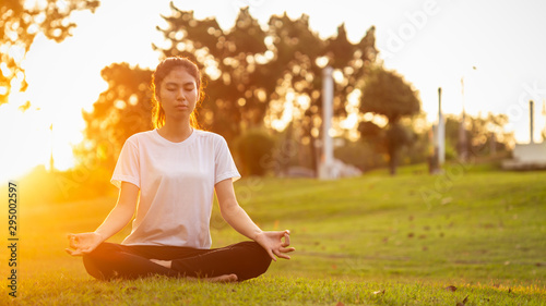 Pretty asian woman doing yoga exercises in the park