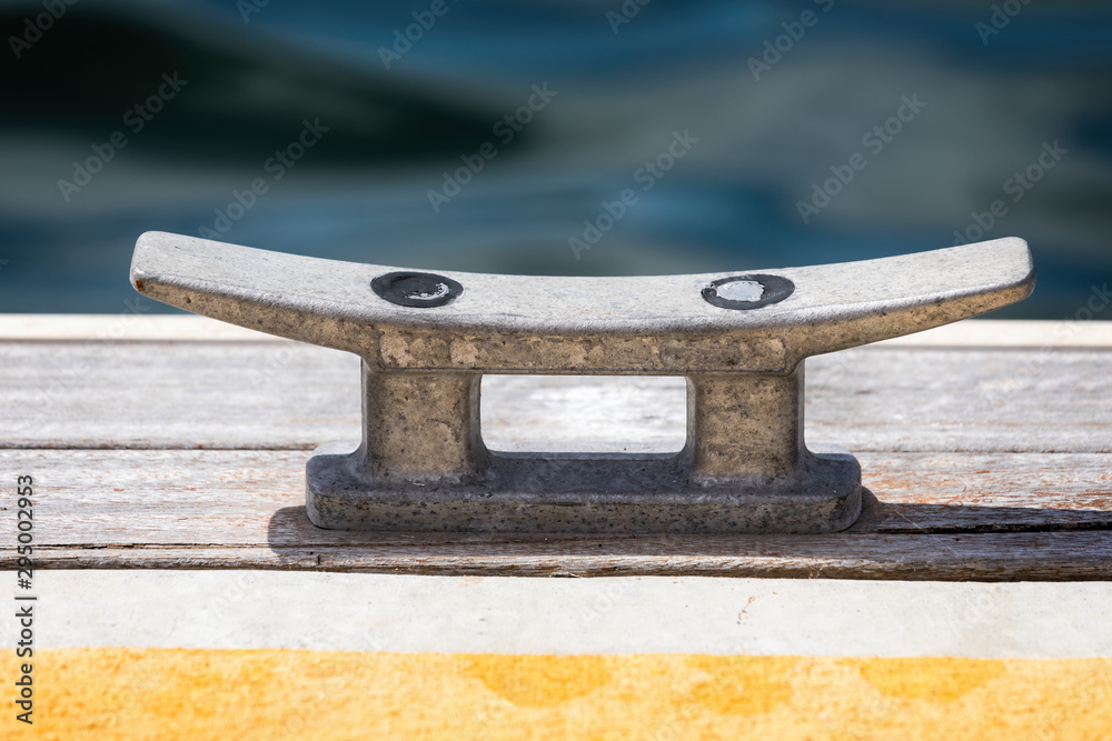 Close up of alloy boat mooring cleat on wooden dock Close up of alloy boat mooring cleat on wooden dock