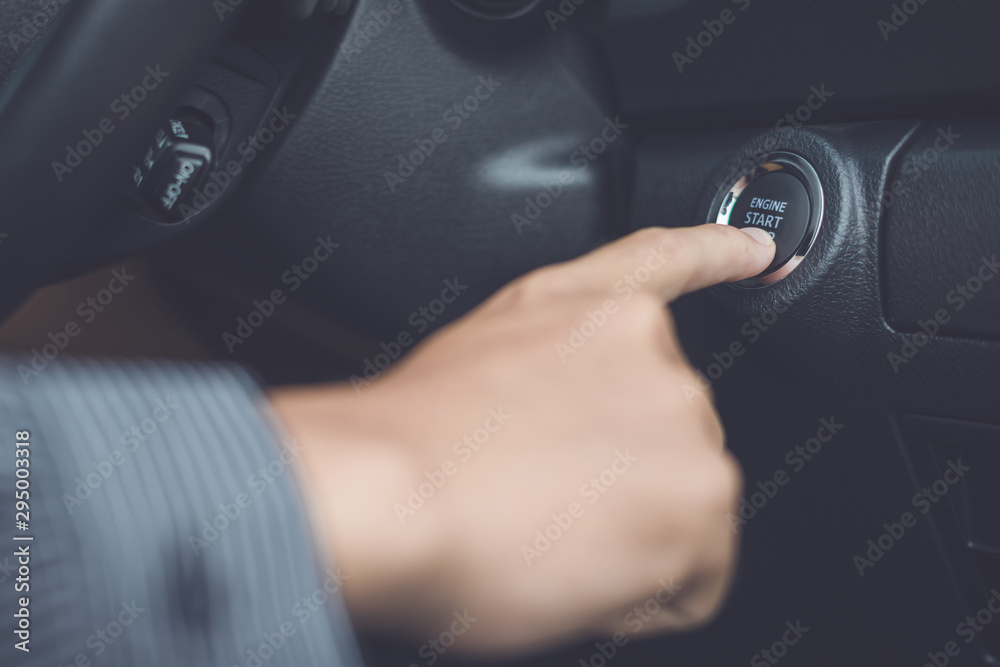 Hand of man pressing button start/stop car engine inside the modern car Hand of man pressing button start/stop car engine inside the modern car