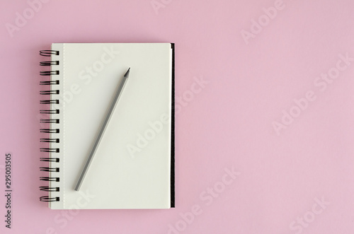 Note pad with pencil composition on pink background.