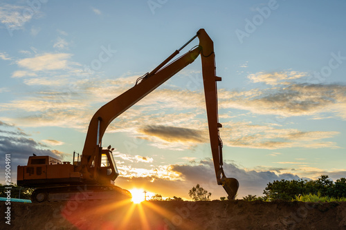 Silhouette of big tracked excavator digging the soil on site
