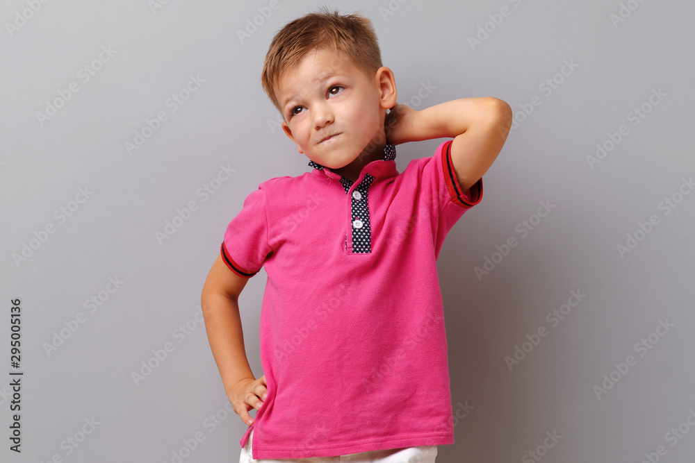 Portrait of thinking little boy standing on a grey background Portrait of thinking little boy standing on a grey background