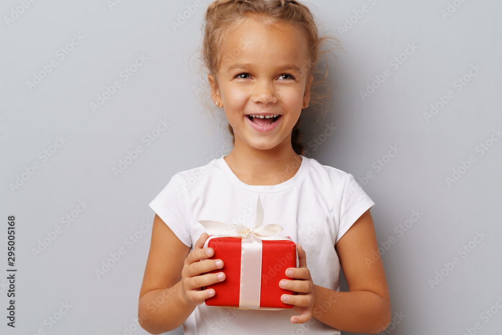 Nice little girl holding a red gift box in her hands Nice little girl holding a red gift box in her hands