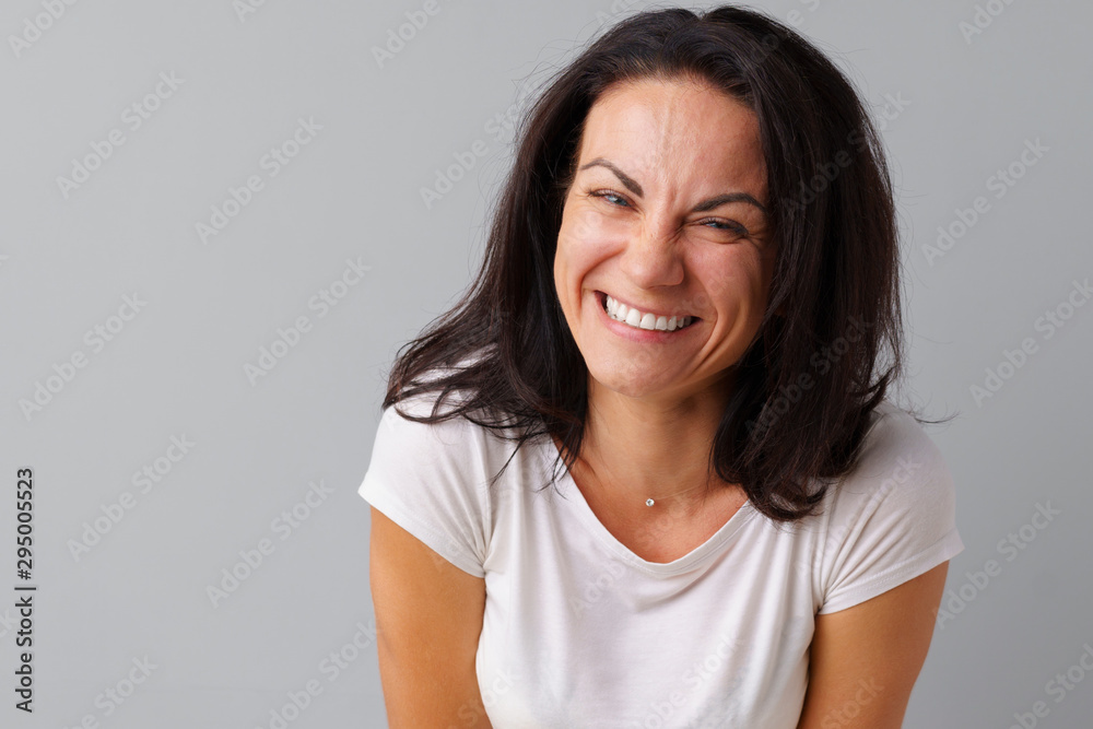 Portrait of joyful brunette young cute woman laughing over a gray background Portrait of joyful brunette young cute woman laughing over a gray background