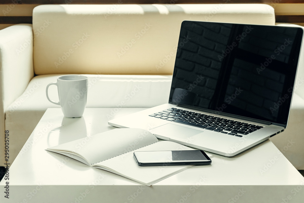 Open laptop on table near sofa, home interior. Freelancer workplace concept Open laptop on table near sofa, home interior. Freelancer workplace concept
