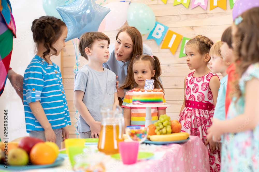 Group of adorable kids, birtday boy and his mom gathered around festive table. Birthday party for preschoolers Group of adorable kids, birtday boy and his mom gathered around festive table. Birthday party for preschoolers